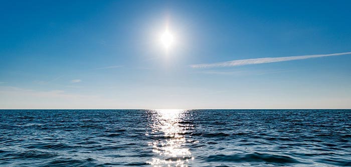 the midday sun directly heating a large body of water
