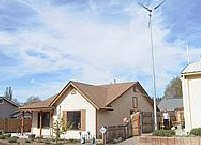 a suburban house with a pole-mounted wind turbine in the yard
